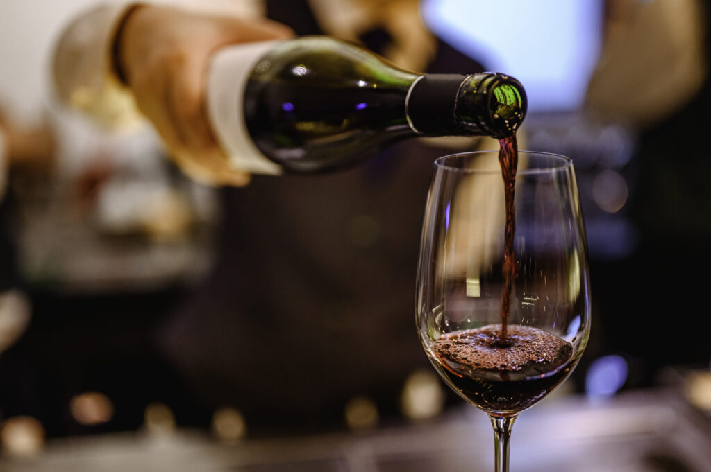 Pouring glass of red wine from a bottle.