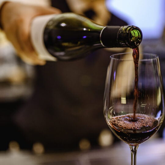Pouring glass of red wine from a bottle.