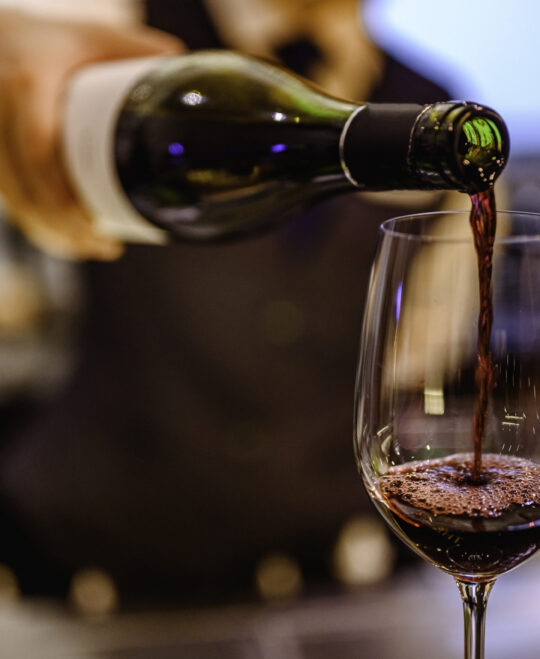 Pouring glass of red wine from a bottle.